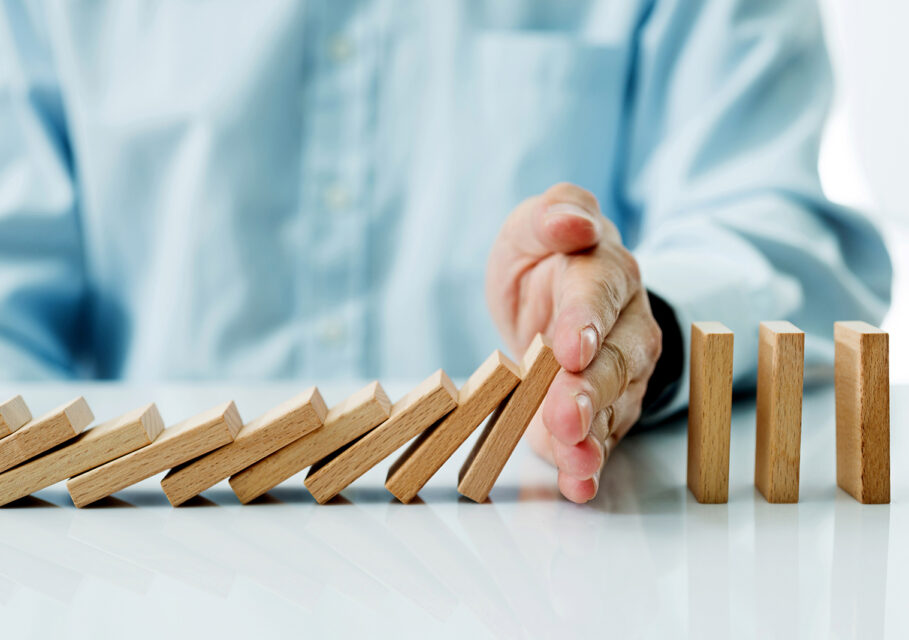 Businessman hand stopping falling blocks on table