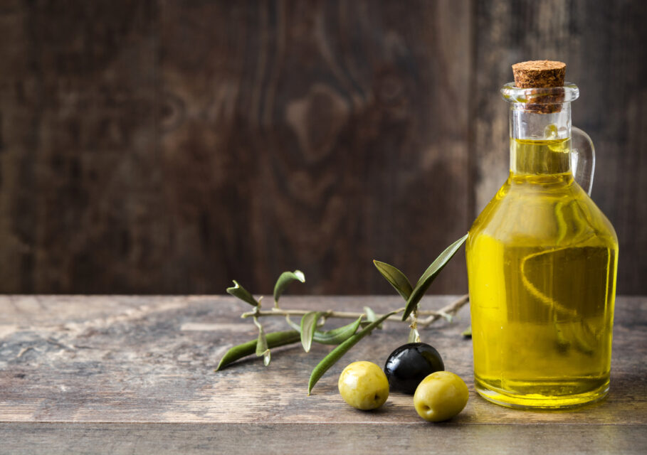 Virgin olive oil in a crystal bottle on wooden background.Copyspace